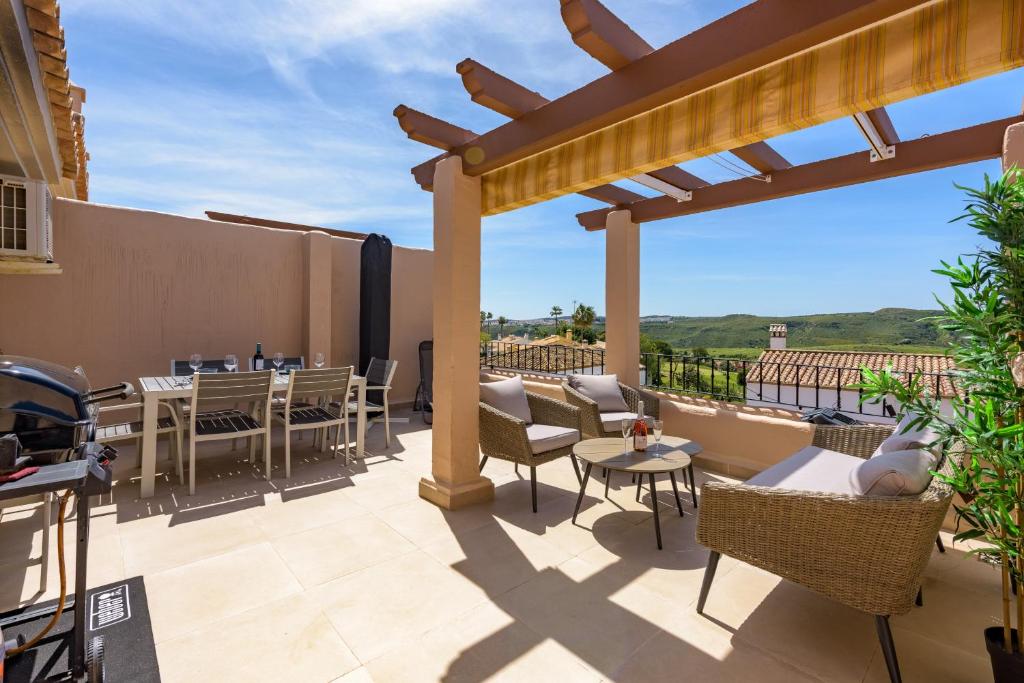 Un patio con sillas y mesas y una pérgola. en 2247-Duplex 3 bedrooms with 2 terraces, en Manilva