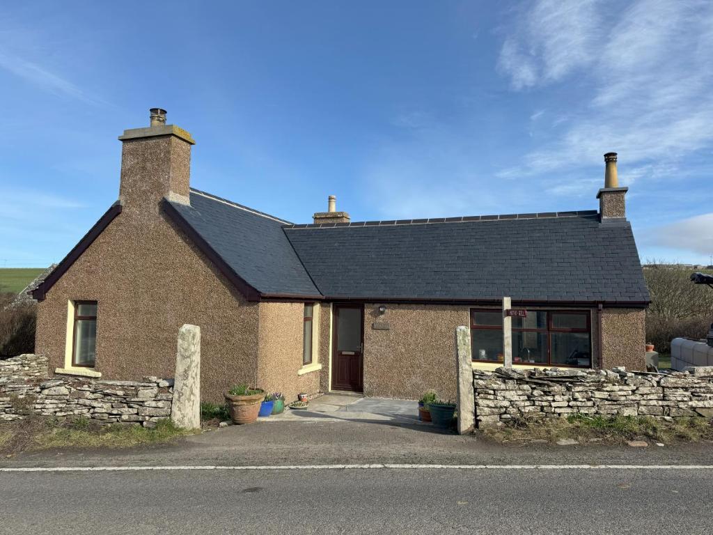 une maison en briques avec un toit noir dans l'établissement Withi-Gill - Cottage - Bay of Ireland Views, à Stromness