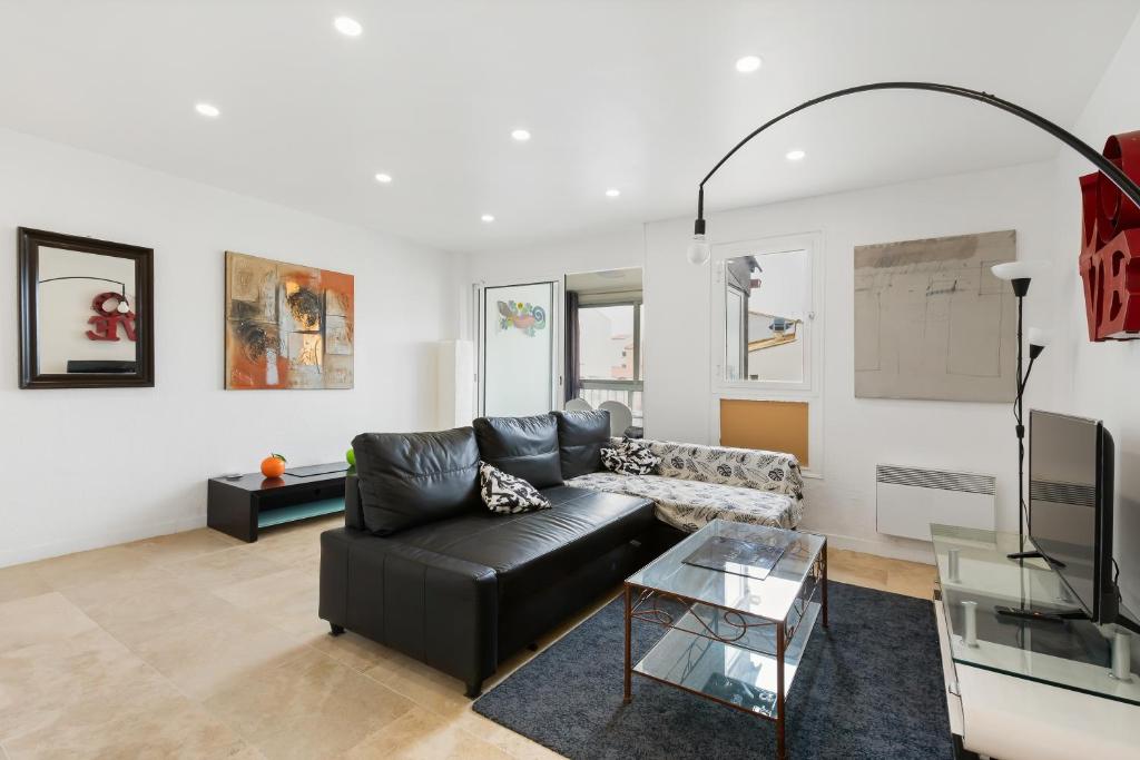 - un salon avec un canapé en cuir noir et une télévision dans l'établissement Cosy et Mer - Piscine partagée, au Cap d'Agde