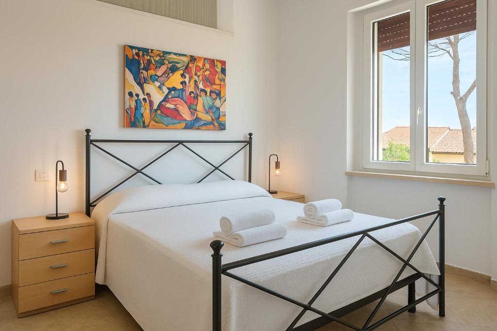 a white bedroom with a bed and a window at Casa Del Mare 50 m dal mare - nuova - Pasqua in Maremma in Castiglione della Pescaia
