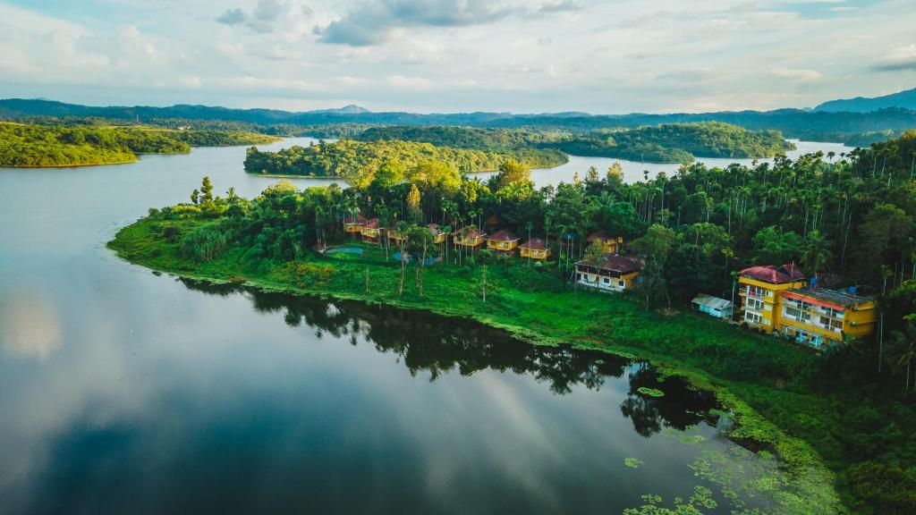 an island in the middle of a river with houses at Karapuzha Village Resort in Wayanad