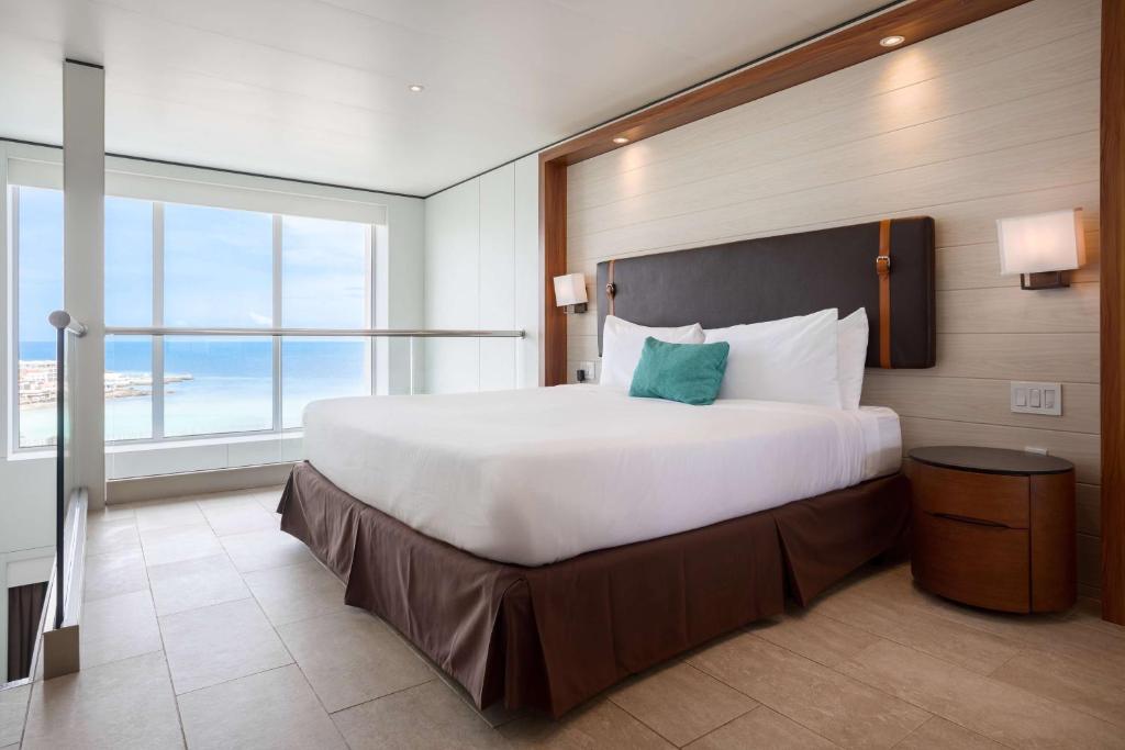 a large bed in a hotel room with a large window at Sonesta Maho Beach All Inclusive Resort Casino & Spa in Maho Reef