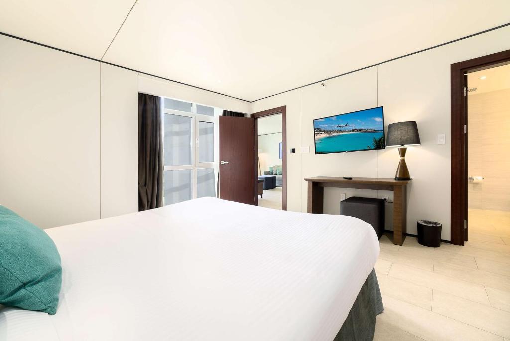 a bedroom with a white bed and a desk at Sonesta Maho Beach All Inclusive Resort Casino & Spa in Maho Reef