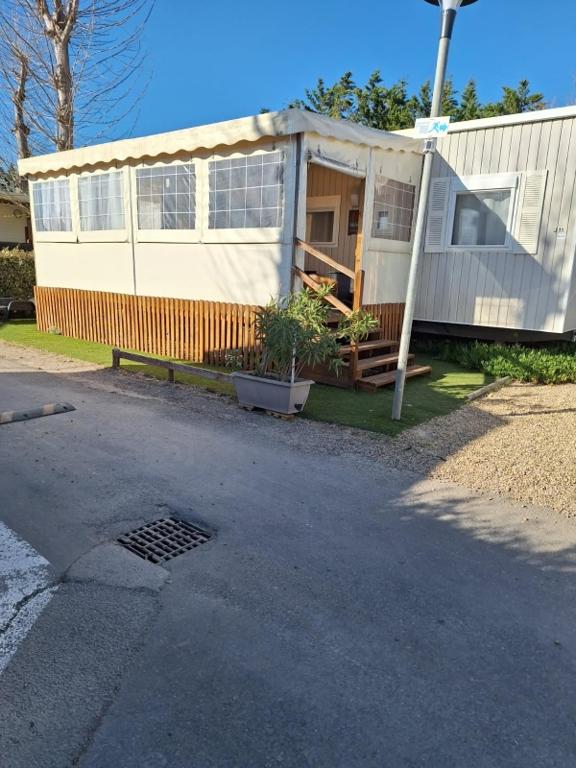 une petite maison avec une terrasse couverte sur le côté. dans l'établissement MOBIL HOME le CHOW-CHOW, à Valras-Plage
