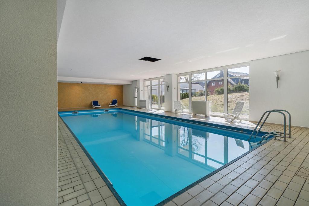 a large pool with blue water in a building at Ferienwohnungen Schönwald in Schonwald im Schwarzwald