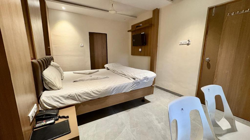 a small room with a bed and two white chairs at Hotel Dwani Palace in Navi Mumbai