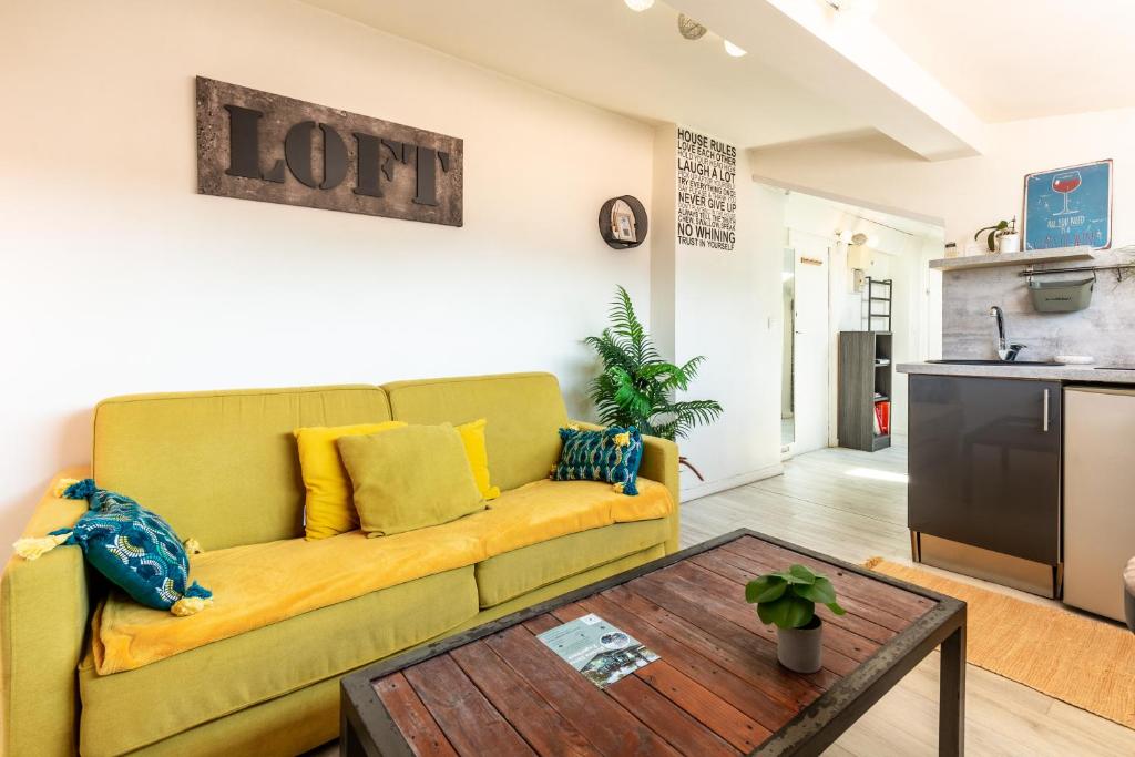 un salon avec un canapé jaune et une table dans l'établissement Homelivia, ATTIC ROOM -Mansardé sous les toits de Nice, à Nice