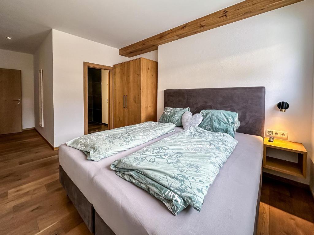 ein Schlafzimmer mit einem großen Bett mit einem hölzernen Kopfteil in der Unterkunft Ours Living Hohe Tauern - inkl Sauna in Hollersbach im Pinzgau