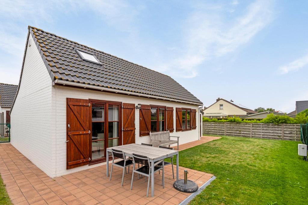 una pequeña casa blanca con una mesa en un patio en Park Haerendycke Vis81, en Wenduine