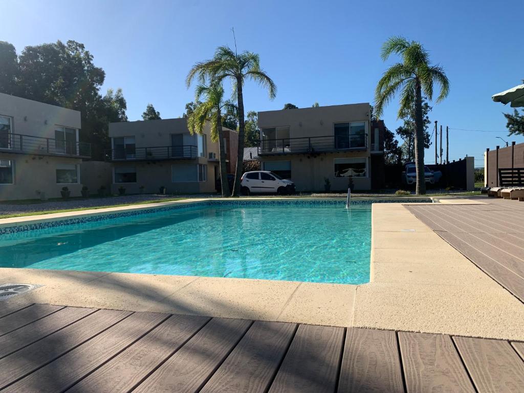 a swimming pool in front of a building with palm trees at Vista24uy Ref1005 in Balneario Solís