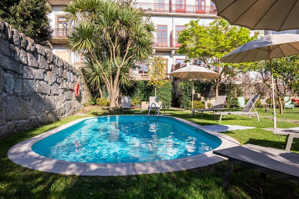 a swimming pool in a yard with an umbrella at Aparthotel Oporto Alves da Veiga in Porto