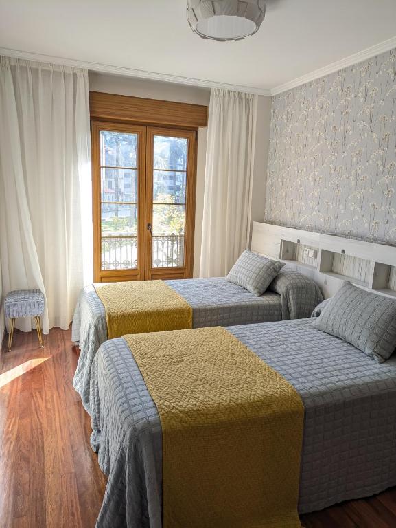 a bedroom with two beds and a window at O Pisiño de Andrés in Caldas de Reis