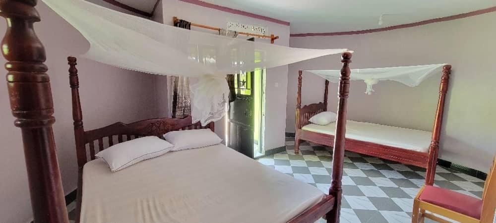 a bedroom with two beds and a canopy bed at AGETAB village City cottages in Soroti