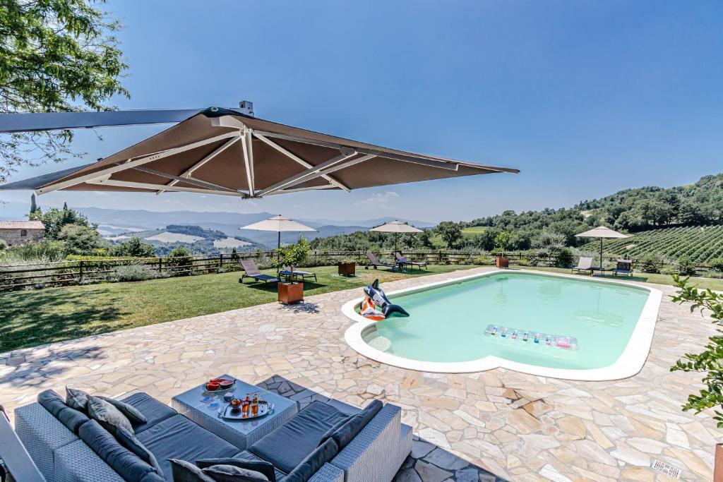 a swimming pool with chairs and an umbrella at Villa Vineyard by Belcanto Villas in Buriano
