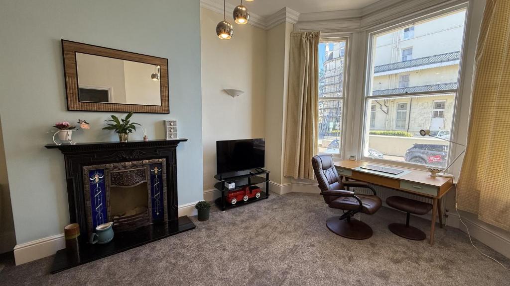 a room with a desk with a computer and a fireplace at 4 Queens Gardens Seaside Apartment in Eastbourne