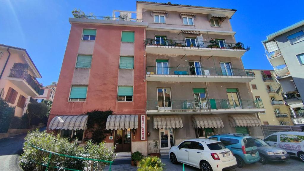 Un edificio alto con coches aparcados delante. en Hotel al Porto, en Imperia