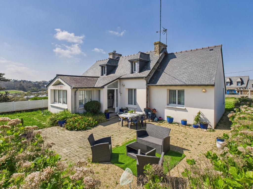 une maison avec une arrière-cour dotée d'une table et de chaises dans l'établissement Maison pour 8 avec grand jardin à 150m de la mer, à Trévou-Tréguignec