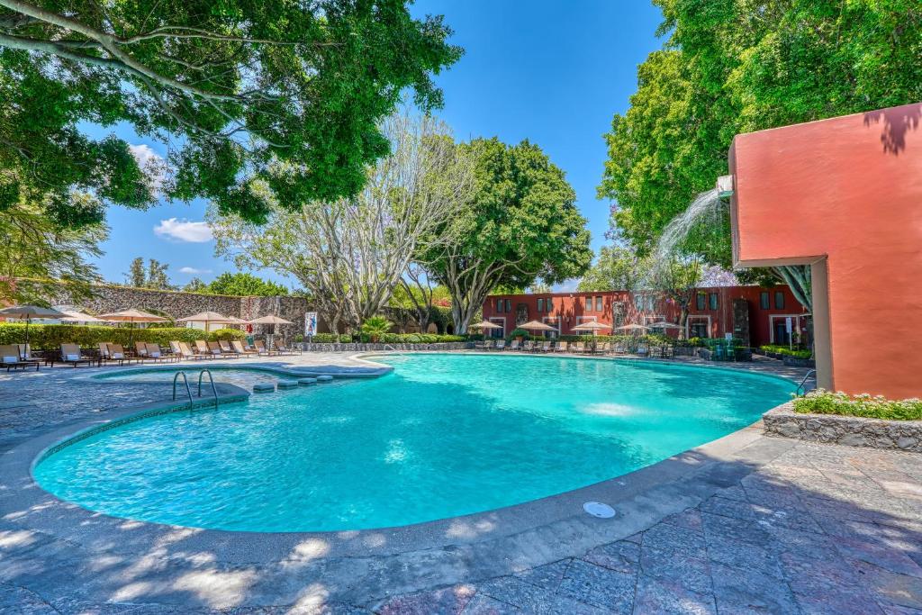 a swimming pool at a resort with trees at Hacienda Jurica by Brisas in Querétaro