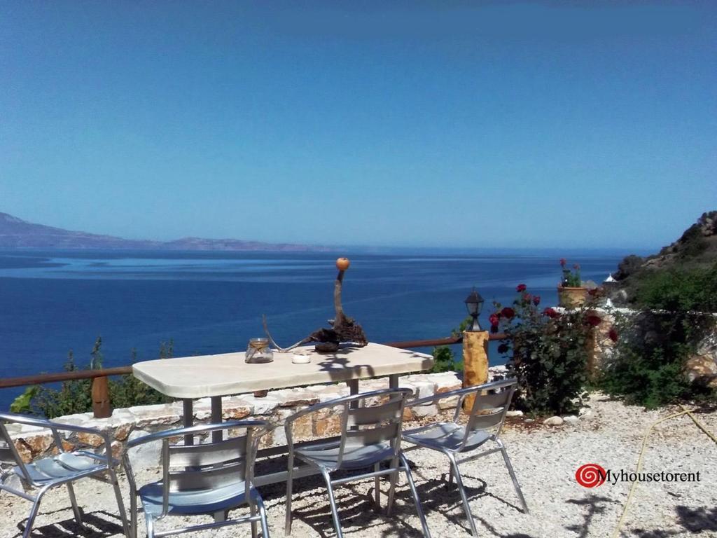 a table and chairs with a view of the ocean at apartment over the sea Private place to swim in Ravdhoúkha
