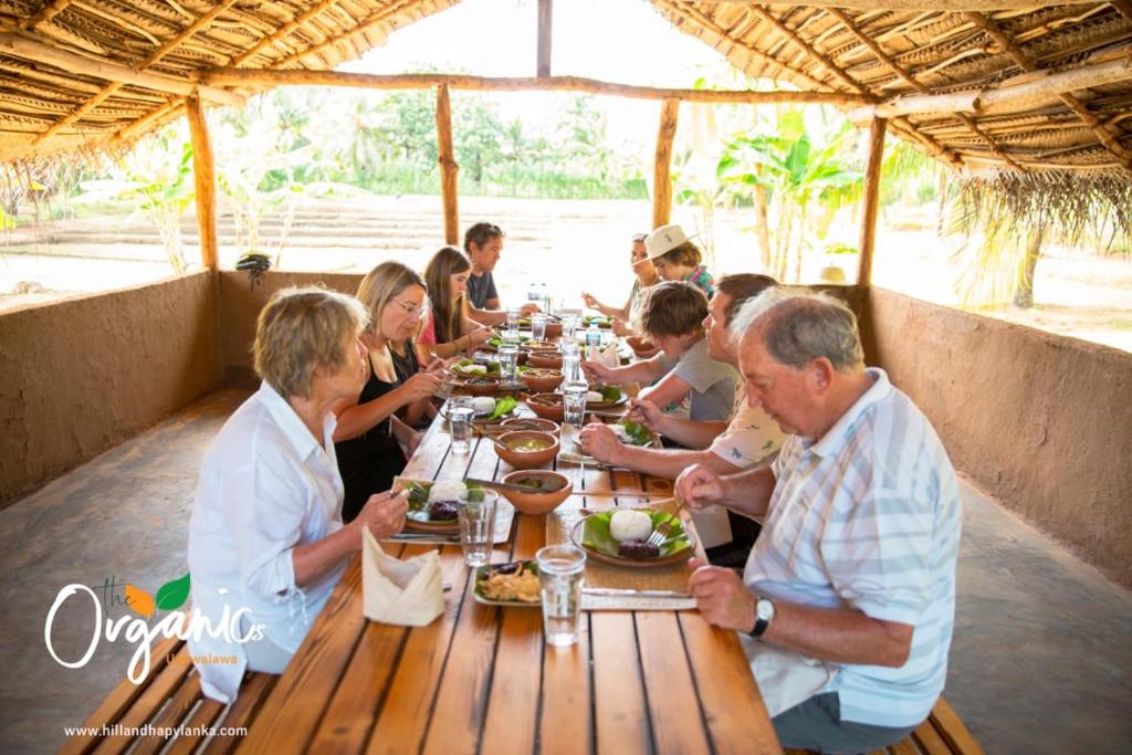 a group of people sitting at a table eating food at Dramatic Green Cottage in Udawalawe