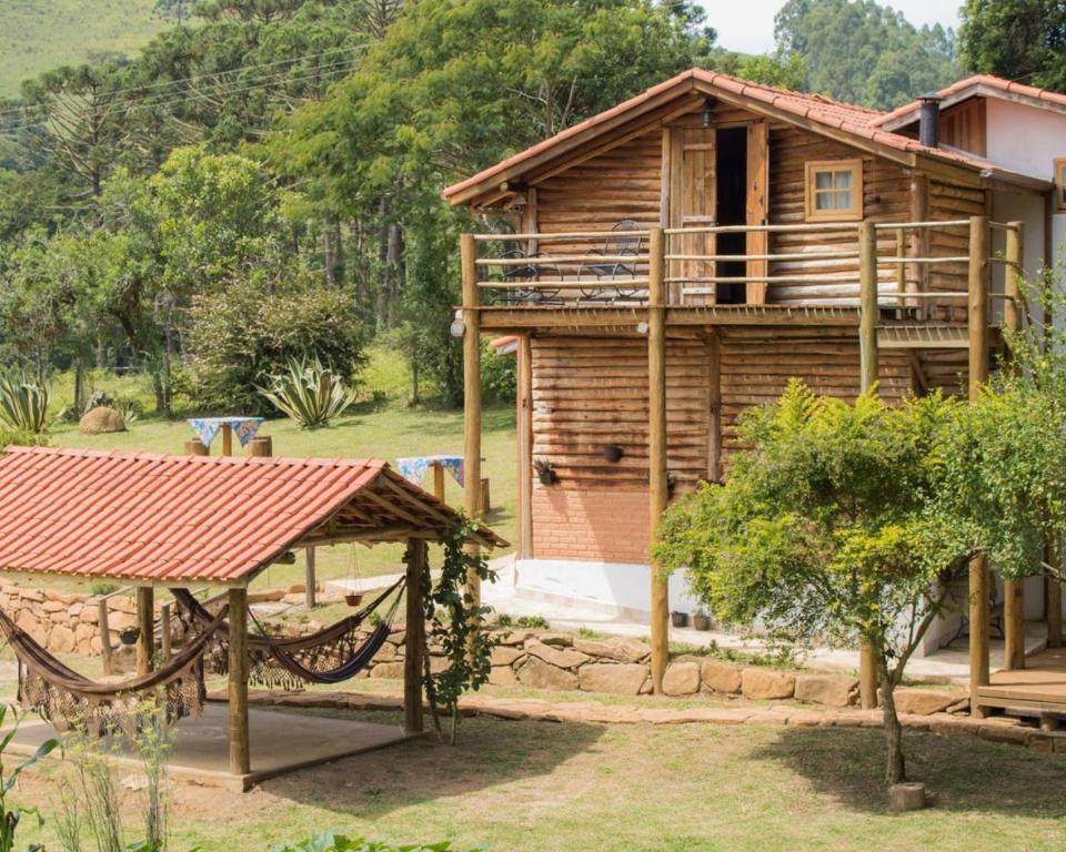 a wooden house with a porch and a tree at Pousada Recanto da Pantera in Cunha