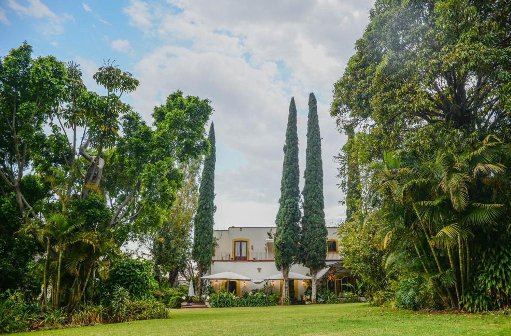 a house in the middle of a yard with trees at Hotel Hacienda Los Laureles in Oaxaca City