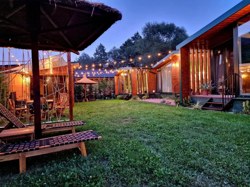 un patio trasero con una casa con luces y césped en Noor House Resort, en Şuncuiuş