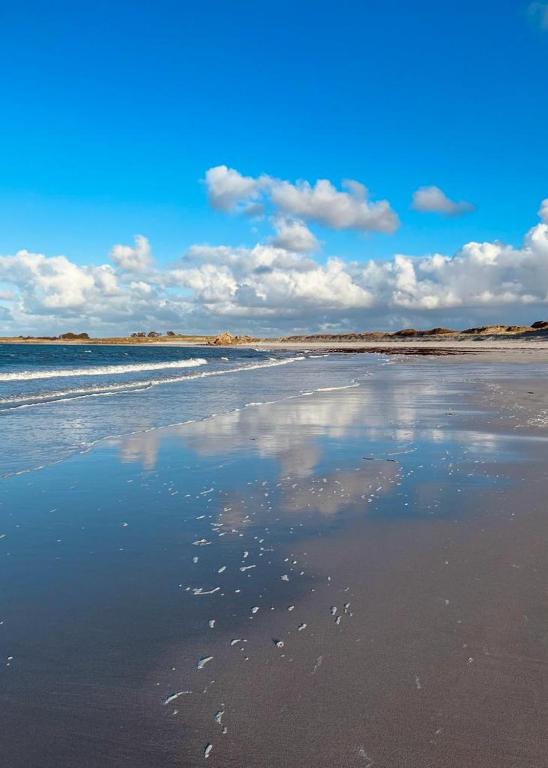 une plage avec une réflexion sur le ciel dans l'eau dans l'établissement Gite de Kervao, Camélias, proche mer (800 mètres), meublé tourisme 3 étoiles, à Ploudalmézeau