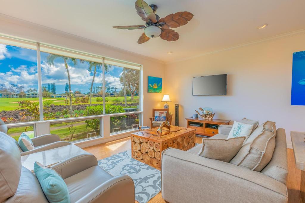 a living room with white furniture and a large window at Hale Emmalani #311 in Princeville