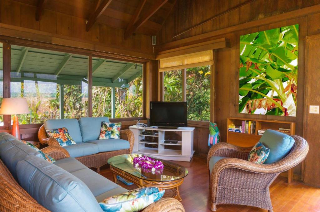 a living room with a blue couch and chairs and a tv at Wainiha Beach Hale in Wainiha