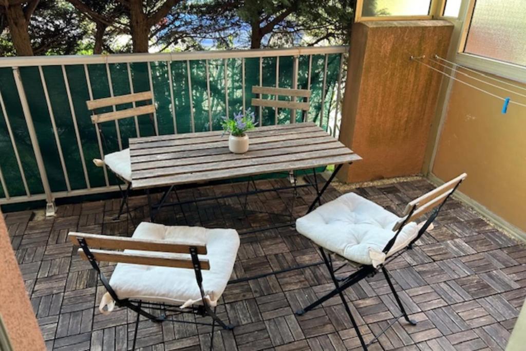 - une table en bois et 2 chaises sur une terrasse couverte dans l'établissement Apartment 20 m from the sea - Cavalaire-sur-Mer, à Cavalaire-sur-Mer