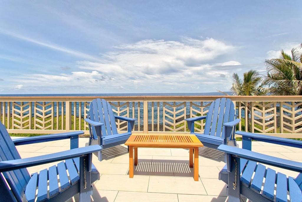 a table and chairs on a balcony with the ocean at Paradise Ocean View in Keaau