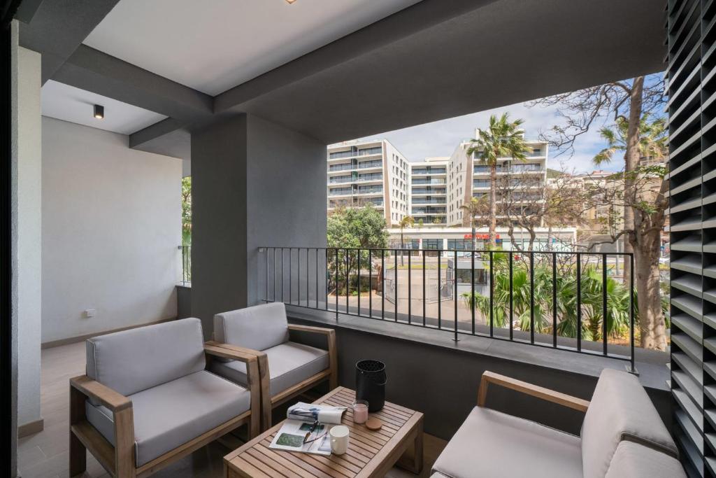 a balcony with two chairs and a table and a window at With pool in Funchal - Acqua Residence V in Funchal