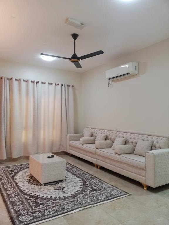 a living room with a couch and a ceiling fan at Al Khashabah Apartment شقة في طريق إزكي - سناو in Mukhtari‘