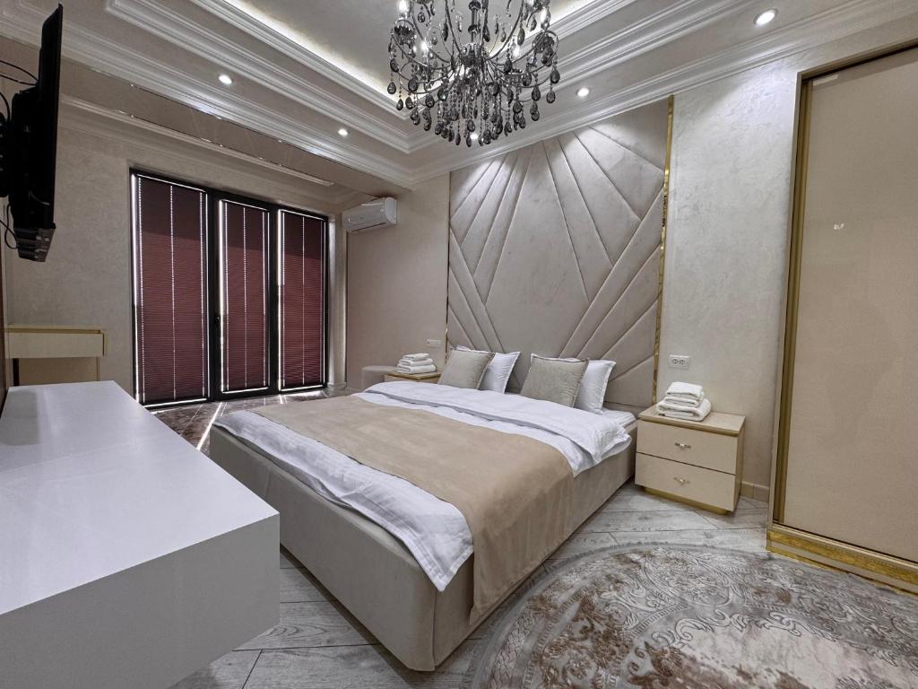 a bedroom with a large bed and a chandelier at Samarkand Premium Apartment in Samarkand