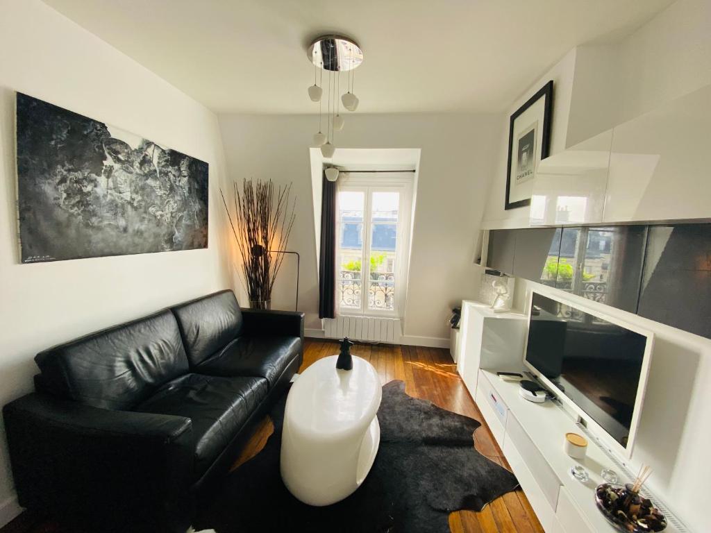 un salon avec un canapé en cuir noir et une table dans l'établissement Turbigo, à Paris