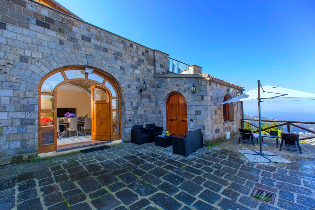 un edificio de piedra con un patio con sombrilla en Villa Sirentum Seaview Pool & Spa, en Sorrento