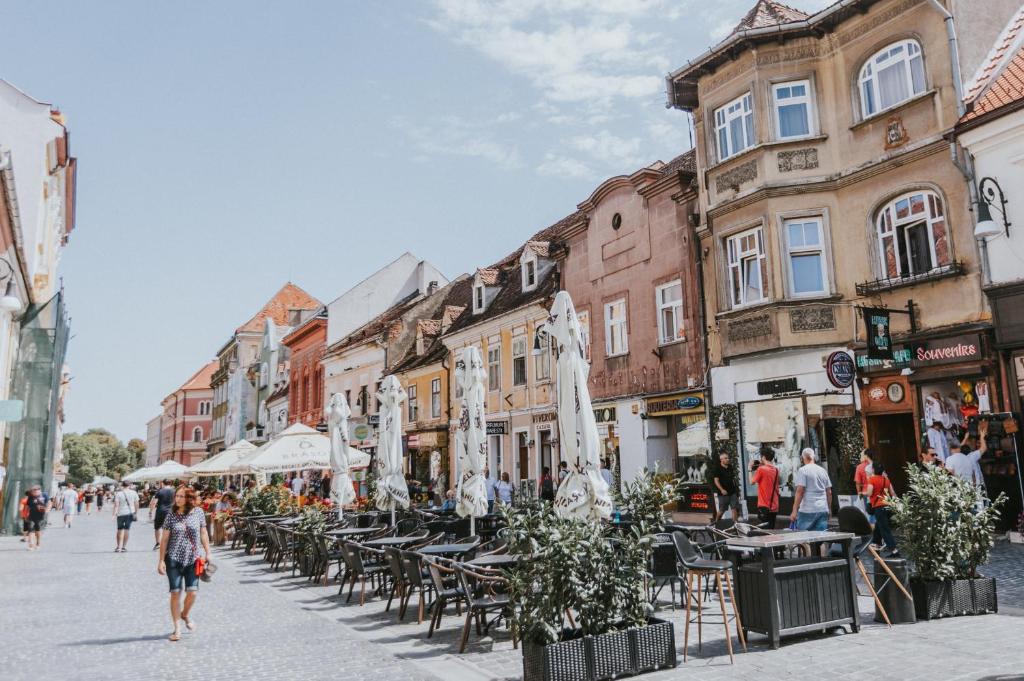 una mujer caminando por una calle con mesas y sillas en Republicii Rustic Apartament in Brașov City Center, en Brasov