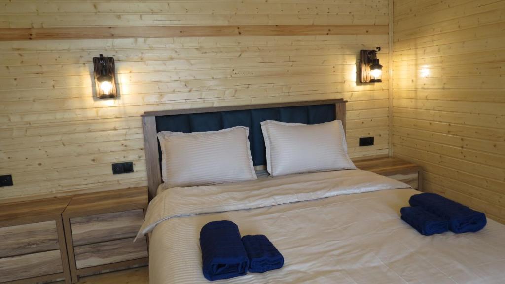 a bedroom with a bed with two blue slippers on it at Cottage nikolozi2 in Arsha