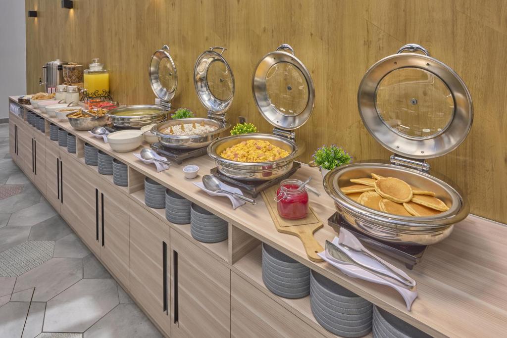 A breakfast buffet with covered hot dishes, fruit and drinks.