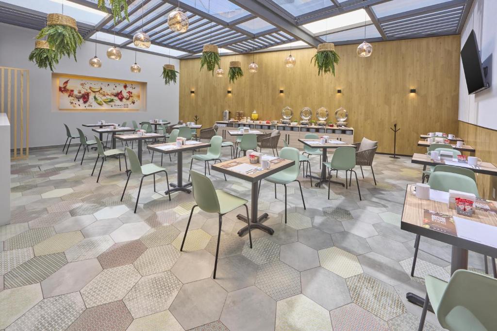 A large breakfast room with many tables, a buffet counter, hanging plants, and a glass canopy.