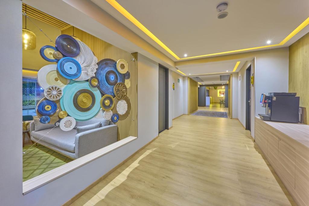 A warmly lit hotel corridor with colorful plate artwork and a small service counter.
