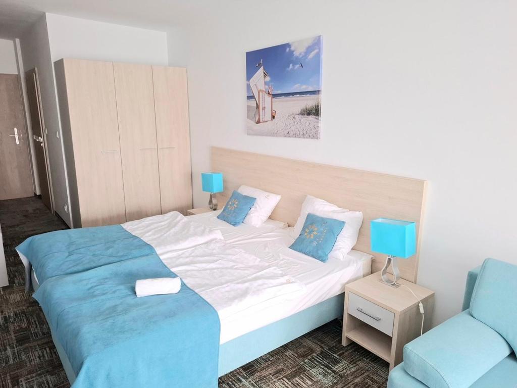 une chambre avec un lit et une chaise bleue dans l'établissement Apartament 104 Wind w Welle, à Grzybowo