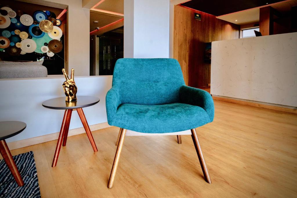 A teal lounge chair and side table in a compact, design-led hotel seating area.