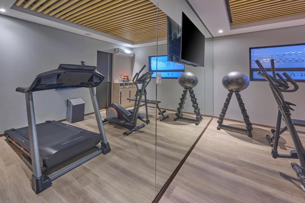 A compact gym with cardio machines, free weights and mirrored walls.