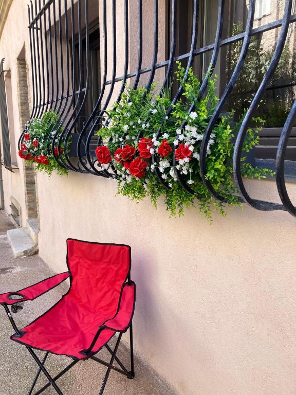 une chaise rouge assise devant une fenêtre fleurie dans l'établissement Picasso Walk Cosy charm in heart of Old Town Antibes AC and WiFi, à Antibes