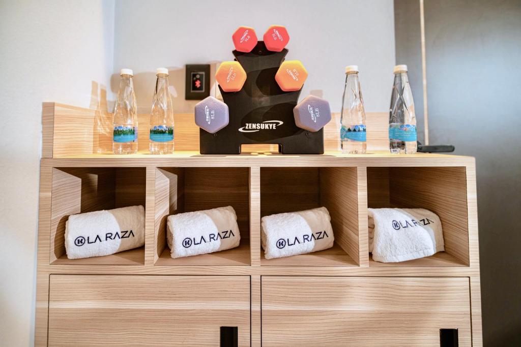 A gym storage cabinet with branded towels, bottled water and a compact dumbbell rack.