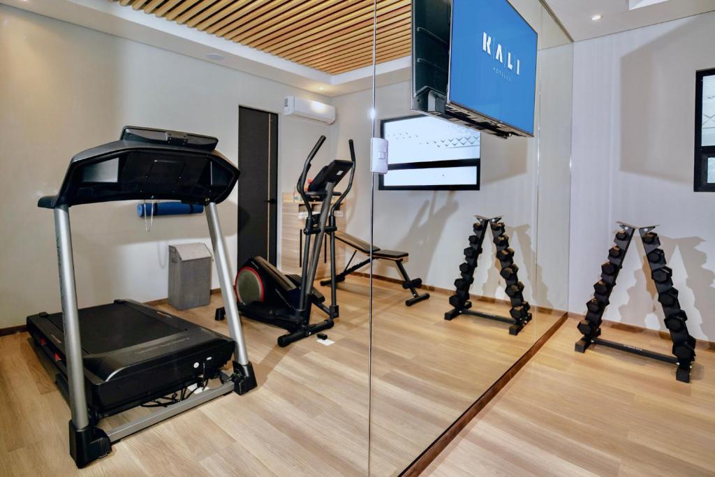 A compact mirrored fitness room with cardio equipment and free weights.