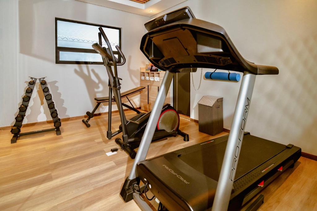 A gym corner centered on a treadmill, with an elliptical and free weights behind it.