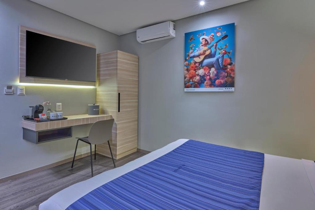A bedroom workspace with a wall-mounted television, desk, and beverage station.